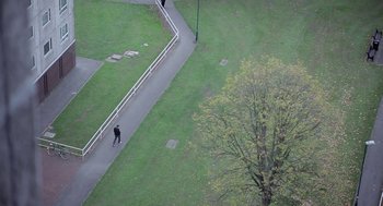 Movie still from “Weekend” (2011), directed by Andrew Haigh – A person walking down a sidewalk near a park; Extreme Wide shot, High angle
