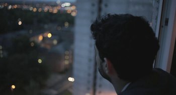 Movie still from “Weekend” (2011), directed by Andrew Haigh – A man looking out of a window at night; Close Up shot, Low angle