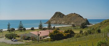 Movie still from “Whale Rider” (2002), directed by Niki Caro – A view of a house with a mountain in the background; Extreme Wide shot, High angle