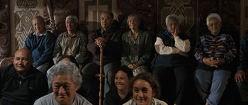 Movie still from “Whale Rider” (2002), directed by Niki Caro – A group of people sitting in a room; Wide shot, High angle