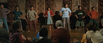 Movie still from “Whale Rider” (2002), directed by Niki Caro – A group of people standing in front of a group of people; Wide shot, Over the shoulder angle