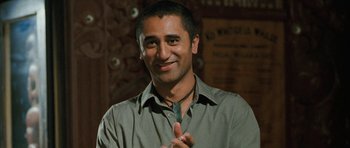 Movie still from “Whale Rider” (2002), directed by Niki Caro – A man in a green shirt smiling for the camera; Close Up shot, Over the shoulder angle