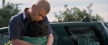 Movie still from “Whale Rider” (2002), directed by Niki Caro – A man is hugging a young girl in front of a car; Medium shot, Over the shoulder angle