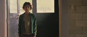 Movie still from “Whale Rider” (2002), directed by Niki Caro – A young man standing in front of an open window; Medium shot, Over the shoulder angle