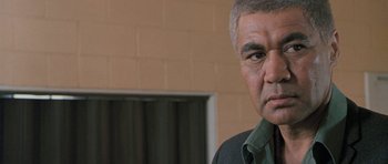 Movie still from “Whale Rider” (2002), directed by Niki Caro – An older man in a green shirt and black shirt; Close Up shot, Low angle