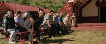 Movie still from “Whale Rider” (2002), directed by Niki Caro – A group of men sitting on a bench in the grass; Wide shot, High angle