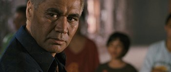 Movie still from “Whale Rider” (2002), directed by Niki Caro – An older man looks at the camera while a young woman looks on; Close Up shot, Over the shoulder angle