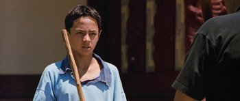 Movie still from “Whale Rider” (2002), directed by Niki Caro – A young man holding a wooden stick in his hand; Close Up shot, High angle