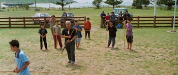 Movie still from “Whale Rider” (2002), directed by Niki Caro – A group of people standing in a field holding sticks; Wide shot, High angle