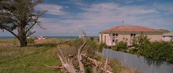 Movie still from “Whale Rider” (2002), directed by Niki Caro – An abandoned house sitting in the middle of a field; Extreme Wide shot, Low angle