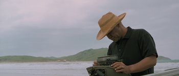 Movie still from “Whale Rider” (2002), directed by Niki Caro – A man in a straw hat looking down at an old typewriter; Medium shot, Low angle