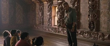 Movie still from “Whale Rider” (2002), directed by Niki Caro – A man standing next to an animal in a room; Wide shot, Over the shoulder angle