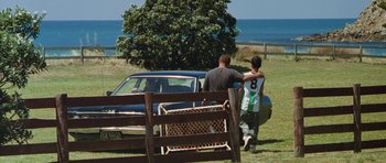 Movie still from “Whale Rider” (2002), directed by Niki Caro – Two men standing in front of a car in a field; Wide shot, Over the shoulder angle