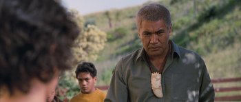 Movie still from “Whale Rider” (2002), directed by Niki Caro – A man wearing a necklace with an arrow on it; Close Up shot, Over the shoulder angle