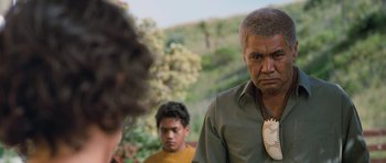 Movie still from “Whale Rider” (2002), directed by Niki Caro – A man in a green shirt is standing next to two other men; Close Up shot, Over the shoulder angle