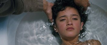 Movie still from “Whale Rider” (2002), directed by Niki Caro – A person is washing a child's hair in a pool of water; Close Up shot, Overhead angle