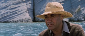 Movie still from “Whale Rider” (2002), directed by Niki Caro – A man wearing a straw hat near a body of water; Close Up shot, Low angle