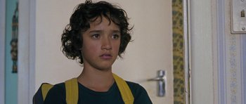 Movie still from “Whale Rider” (2002), directed by Niki Caro – A young boy with curly black hair wearing a green t - shirt; Close Up shot, Low angle