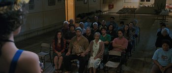 Movie still from “Whale Rider” (2002), directed by Niki Caro – A group of people sitting in chairs in a room; Wide shot, High angle