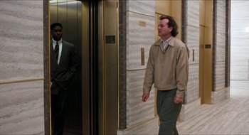 Movie still from “What About Bob?” (1991), directed by Frank Oz – A man in a tan jacket is walking in an elevator; Wide shot, Low angle