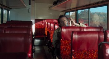 Movie still from “What About Bob?” (1991), directed by Frank Oz – A man sitting on a red seat on a bus; Medium shot, High angle