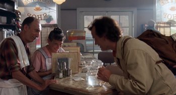Movie still from “What About Bob?” (1991), directed by Frank Oz – A man and a woman sitting at a table in a restaurant; Medium shot, Over the shoulder angle
