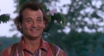 Movie still from “What About Bob?” (1991), directed by Frank Oz – A man smiling for the camera in front of a tree; Close Up shot, Low angle