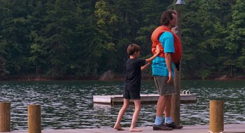 Movie still from “What About Bob?” (1991), directed by Frank Oz – A man standing next to a child on a dock; Wide shot, Over the shoulder angle