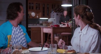 Movie still from “What About Bob?” (1991), directed by Frank Oz – Two people sitting at a dinner table eating food; Medium shot, Over the shoulder angle