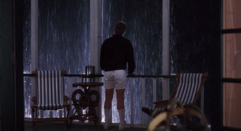 Movie still from “What About Bob?” (1991), directed by Frank Oz – A man standing in front of a window looking out at a waterfall; Wide shot, Low angle