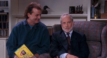 Movie still from “What About Bob?” (1991), directed by Frank Oz – Two men sitting on a couch in a living room; Medium shot, High angle