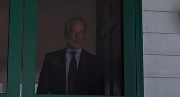 Movie still from “What About Bob?” (1991), directed by Frank Oz – A man wearing a suit and tie standing in front of a window; Medium shot, Low angle