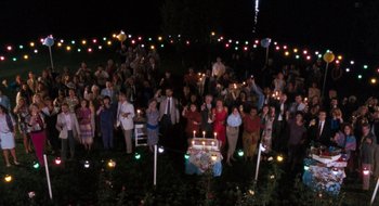 Movie still from “What About Bob?” (1991), directed by Frank Oz – A group of people standing around a table with lit candles on top of it; Extreme Wide shot, High angle