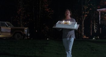 Movie still from “What About Bob?” (1991), directed by Frank Oz – A woman carrying a cake with lit candles on it; Wide shot, High angle
