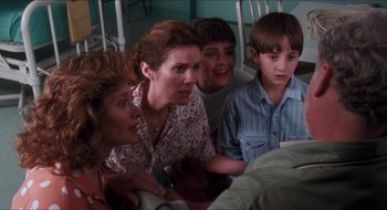 Movie still from “What About Bob?” (1991), directed by Frank Oz – A group of people sitting in a room looking at something; Medium shot, Over the shoulder angle