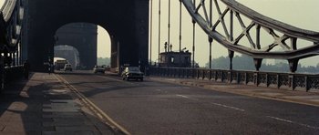 Movie still from “What Have You Done to Solange?” (1972), directed by Massimo Dallamano – Cars driving on a road under a large bridge; Extreme Wide shot, High angle