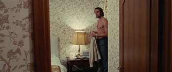 Movie still from “What Have You Done to Solange?” (1972), directed by Massimo Dallamano – A shirtless man standing in a room with a lamp; Medium shot, Low angle