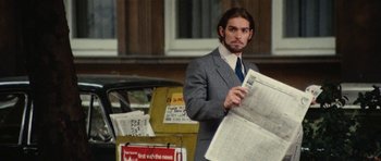Movie still from “What Have You Done to Solange?” (1972), directed by Massimo Dallamano – A man in a suit and tie holding a newspaper; Medium shot, Low angle