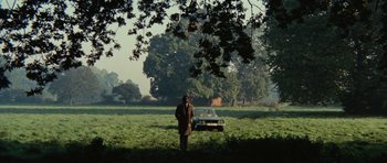 Movie still from “What Have You Done to Solange?” (1972), directed by Massimo Dallamano – A man standing in a field next to a parked car; Extreme Wide shot, High angle