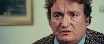 Movie still from “What Have You Done to Solange?” (1972), directed by Massimo Dallamano – An older man looking sad while wearing a jacket; Close Up shot, Over the shoulder angle