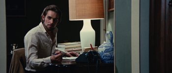 Movie still from “What Have You Done to Solange?” (1972), directed by Massimo Dallamano – A man sitting at a desk writing on a piece of paper; Medium shot, Low angle