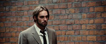 Movie still from “What Have You Done to Solange?” (1972), directed by Massimo Dallamano – A man wearing a suit and tie standing in front of a brick wall; Close Up shot, Low angle