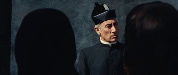 Movie still from “What Have You Done to Solange?” (1972), directed by Massimo Dallamano – An old man wearing a black hat and a black suit; Close Up shot, Over the shoulder angle