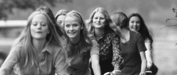 Movie still from “What Have You Done to Solange?” (1972), directed by Massimo Dallamano – A group of young women riding bikes down a street; Medium shot, Low angle