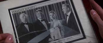 Two men and a woman in tuxedos holding an award