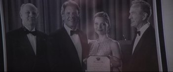 Movie still from “What Lies Beneath” (2000), directed by Robert Zemeckis – An older man standing next to an older woman holding an award; Extreme Close Up shot, Low angle