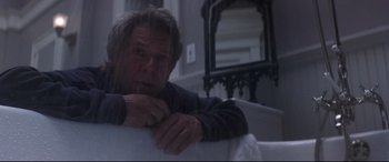 Movie still from “What Lies Beneath” (2000), directed by Robert Zemeckis – A man sitting on a couch in front of a mirror; Medium shot, Low angle