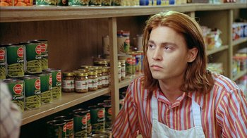 Movie still from “What's Eating Gilbert Grape” (1993), directed by Lasse Hallström – A man in a striped shirt in front of shelves of canned goods; Close Up shot, Low angle