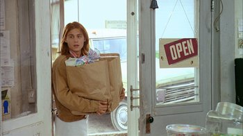 Movie still from “What's Eating Gilbert Grape” (1993), directed by Lasse Hallström – A woman carrying a bag of groceries into a store; Medium shot, Low angle