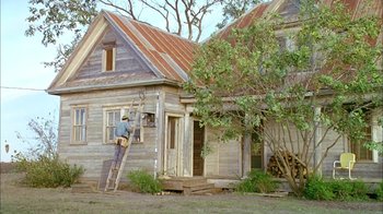 Movie still from “What's Eating Gilbert Grape” (1993), directed by Lasse Hallström – A man standing on a ladder outside of an old house; Wide shot, Low angle